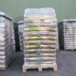 Paleta pelletu drzewnego dimplex na tle innych palet przed magazynem