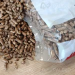 pellet lapwood w worku rozsypany, dziura z przodu, biały worek z żółtym i czerwonym elementem płomienia