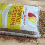 pellet lapwood w worku rozsypany, biały worek z żółtym i czerwonym elementem płomienia