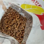 pellet lapwood w worku rozsypany, dziura z widokiem na pellet, biały worek z żółtym i czerwonym elementem płomienia