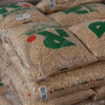 Pellet drzewny Rezult w przezroczystym worku z zielonymmi napisami, leżący worek, zbliżenie na worek, kilka worków leżących na sobie