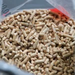 Pellet drzewny Rezult w przezroczystym worku z zielonymmi napisami, leżący worek, zbliżenie na worek, rozsypany pellet luzem